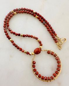 This statement necklace is on-trend and can serve as a layering necklace or hold its own by itself. Beautiful Red Jasper stones are highlighted by non-tarnish gold plated pewter faceted beads and a decorative non-tarnish gold plated pewter hook and eye clasp. Natural Gemstone Necklace. Red Jasper beads are 4mm round faceted round. Red Jasper is associated with grounding, stability, vitality, protection, emotional stability, passion, and spiritual alignment. Throughout history, turquoise has been Beaded Jasper Round Beads Jewelry, Beaded Jasper Jewelry, Beaded Jasper Jewelry With Round Beads, Handmade Jasper Round Beads Necklaces, Gift Jasper Beaded Necklaces, Bohemian Jasper Necklace With Polished Beads, Beaded Jasper Necklace, Jasper Gemstone Beads Necklaces For Jewelry Making, Artisan Wire Wrapped Necklaces With Round Beads