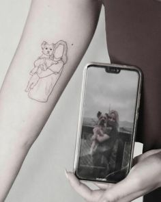 a person holding a cell phone with a drawing on the back of their left arm