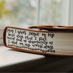 an open book with writing on it sitting on a window sill next to a window