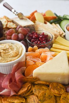 an assortment of cheeses, crackers and fruit on a platter