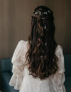 the back of a woman's head with long hair and flowers in her hair