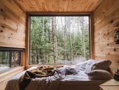 a bed sitting under a window in a bedroom next to a wooden wall and floor