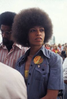 a woman with an afro standing in front of a crowd