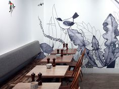 an artistic wall mural in a restaurant with wooden tables and chairs