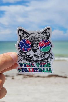 a hand holding up a sticker with a cat wearing sunglasses