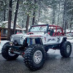 a white jeep parked in front of a cabin on a snowy day with trees and snow covered ground