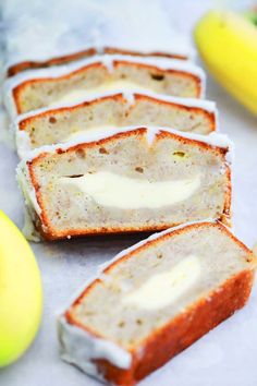 slices of banana bread with white frosting on them and bananas in the back ground