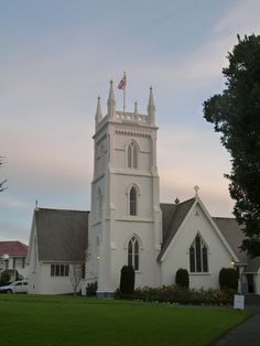 a white church with a flag on the top of it's steeple and grass in front