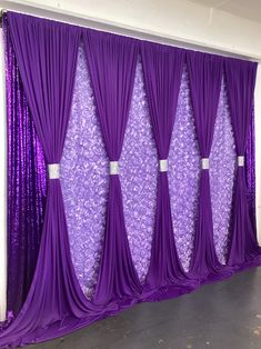 purple drapes are hanging on the wall in front of an open door with silver sequins