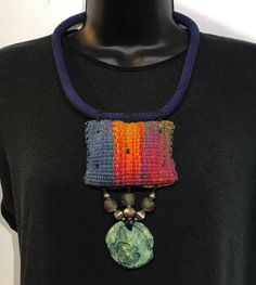 a woman wearing a black shirt with a multicolored necklace hanging from it's chest