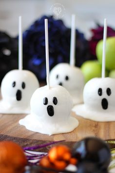 marshmallows with ghost faces are sitting on a cutting board next to halloween decorations