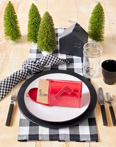 a place setting with black and white checkered table cloth, napkins, silverware, and red utensils