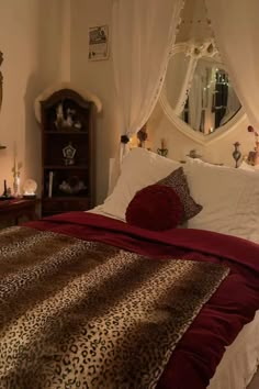 a bedroom with a leopard print comforter and red pillows on the bed, next to a mirror