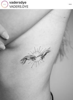 a woman's stomach with the creation of hands tattoo on her left side ribcage