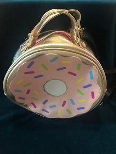 Betsy Johnson 11" donut handbag/purse in gently used condition, gold with pink donut and sprinkles. This item has top handles(7.5") and a removable strap that adjusts(57") with a top zipper closure. There are no interior pockets and the width is 4.5". Please see all photos as part of the description. Ships free in the USA only. Cute Gold Bags For Everyday Use, Cute Gold Bag, Pink Donuts, Betsy Johnson, Top Handle, Makeup Bag, Purses And Handbags, Top Handle Bag, Handbags