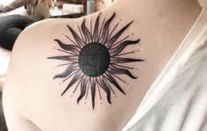 a woman's shoulder with a sun tattoo on it