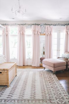 a living room filled with furniture and pink curtains