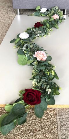 flowers and greenery are laid out on the floor to make a long line for an arrangement