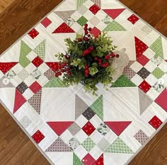 a potted plant sitting on top of a table covered in red, green and white quilts