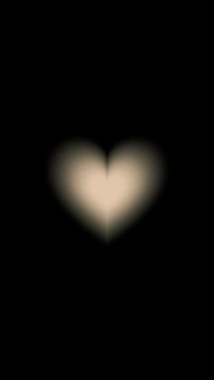 a blurry image of a white heart in the middle of black background with light coming from it