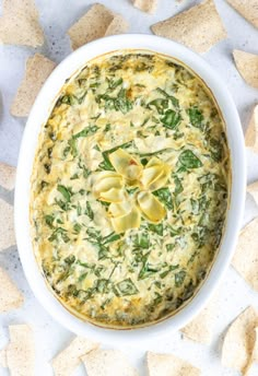 spinach and artichoke dip in a white bowl surrounded by tortilla chips