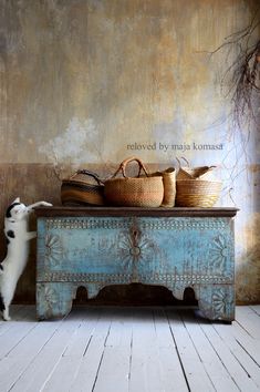 a cat standing on its hind legs in front of a blue bench with baskets on it