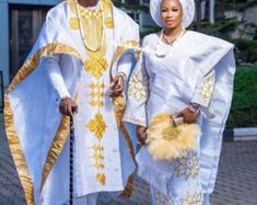 two people dressed in white and gold standing next to each other on a brick walkway