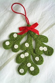 a green christmas ornament hanging from a red ribbon