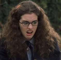 a woman with long curly hair wearing glasses and a tie is making an angry face