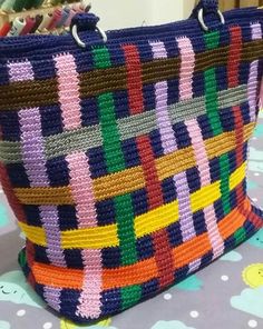 a multicolored woven purse sitting on top of a blue and white table cloth