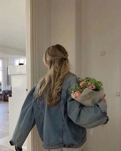 a woman is holding a bouquet of flowers in her hand while walking down the hallway