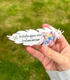 a person holding up a butterfly shaped sticker in their hand with the words butterflies appear when loved ones are near