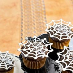 cupcakes decorated with white icing and spider web decorations