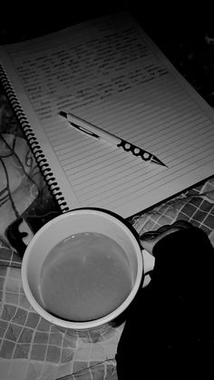 a cup of coffee sitting on top of a table next to a notebook