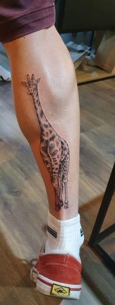 a giraffe tattoo on the leg of a person