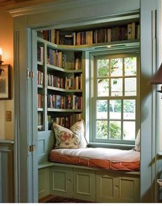 a window seat in the corner of a room with bookshelves full of books