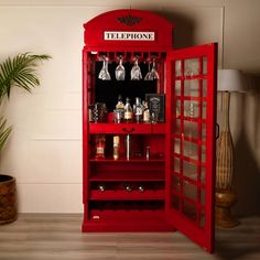 a red phone booth with wine glasses and liquor bottles on the shelf next to it