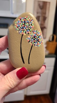 a hand holding a painted rock with sprinkles on it