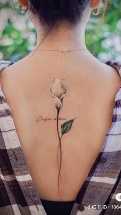 the back of a woman's neck with a flower tattoo on it