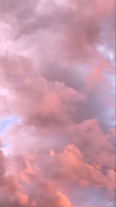 the airplane is flying high in the sky with pink and blue clouds behind it on a cloudy day