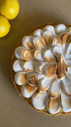 there is a lemon and meringue pie on the table next to some lemons