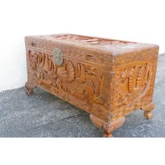 an ornate carved wooden box sitting on the ground next to a white wall and cement floor