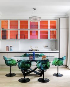 a dining room table with chairs around it and an orange cabinet behind the glass doors