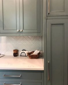 a kitchen with gray cabinets and white counter tops