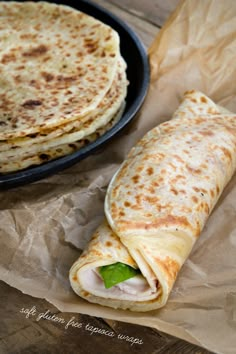 two quesadillas sitting on top of brown paper next to a pan filled with food