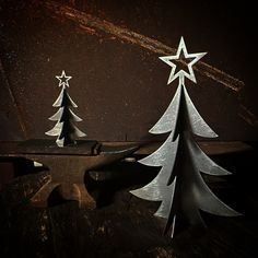 three metal christmas trees sitting on top of a wooden table next to each other in front of a dark background