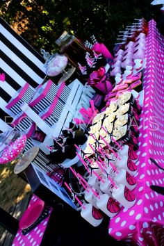 a table with pink and white desserts on it in front of a black and white striped chair