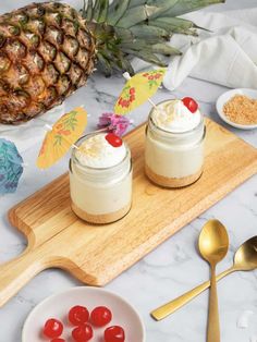 two desserts are sitting on a cutting board with spoons and pineapple in the background