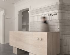 a person standing in front of a counter with the words coosh on it and an open door