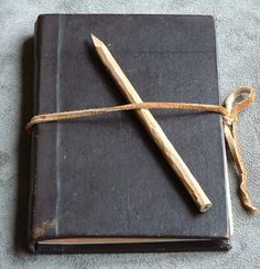 an old book with a wooden stick tied up to it's cover on the floor